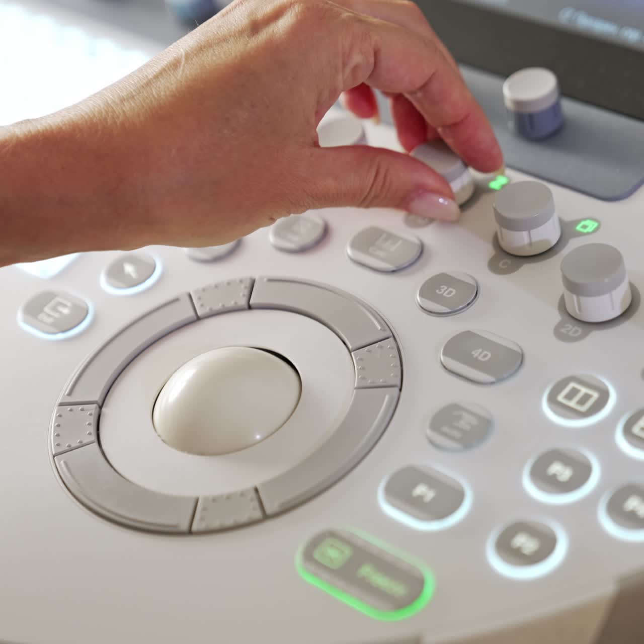 Female medic's hand turning the handles on the medical equipment. Close up. Ultrasound machine keyboard from top view