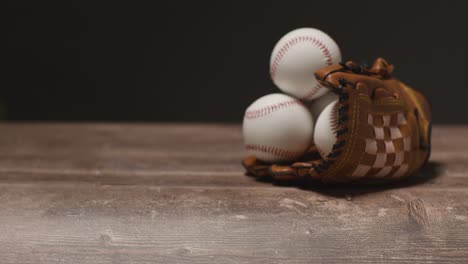 baseball still life with person picking up ball from catchers mitt on wooden floor 3