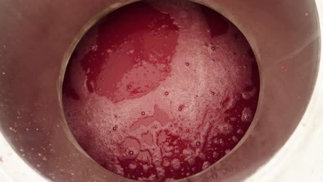 mirando hacia abajo en una tina de vino tinto en una fábrica de vino en preparación para el embotellado