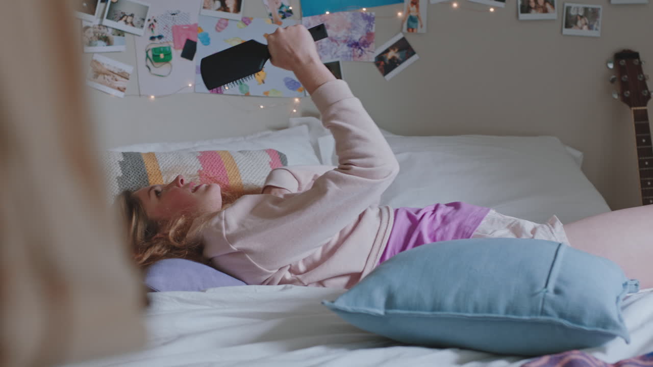 una adolescente feliz bailando en la cama en casa con música disfrutando de celebrar el fin de semana divirtiéndose cantando con pijama en el dormitorio