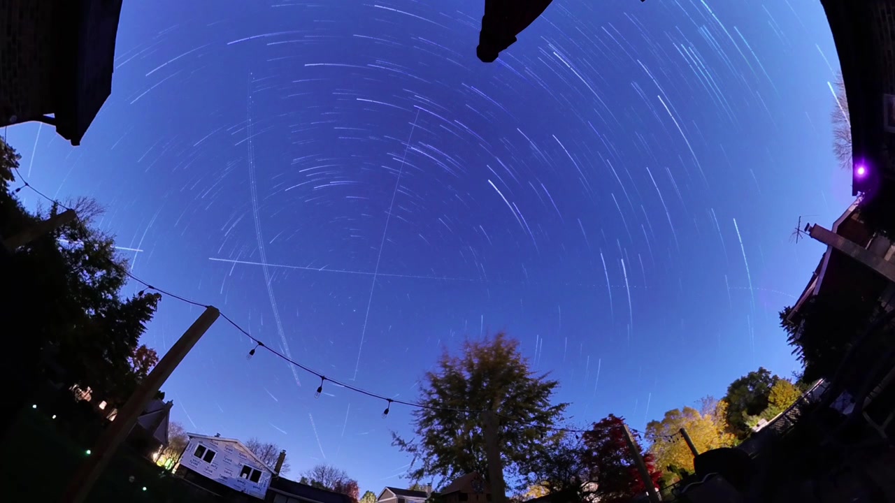 Vista em time-lapse de estrelas se movendo pelo céu noturno, criando rastros e padrões de longa exposição.