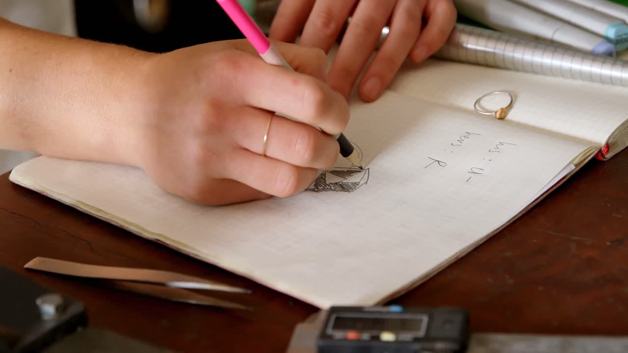 diseñadora de joyas dibujando un boceto en el registro 4k