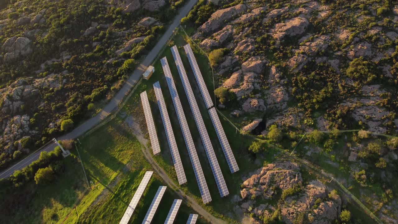 Top down aerial of Photovoltaic Solar Farm power station, tilt reveals wind turbine by sea