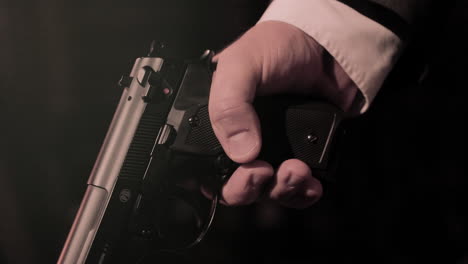 close up on mafia man in suit's hands holding a pistol