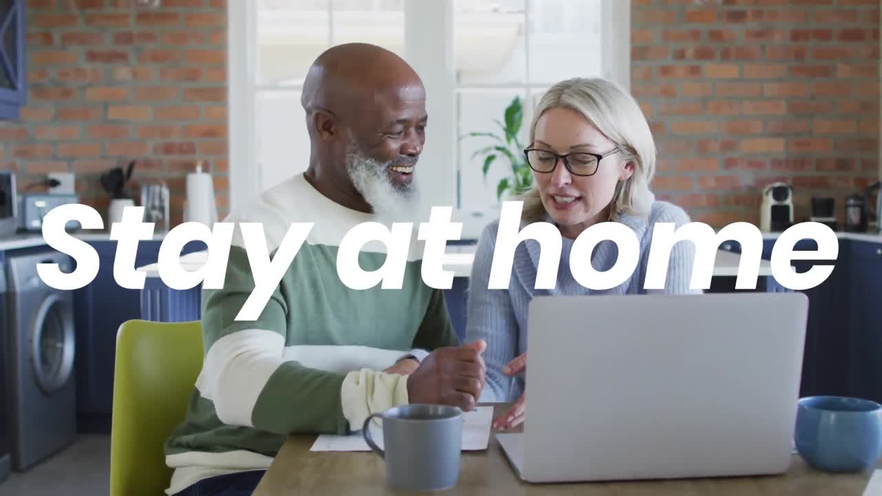 Animation du texte "restez à la maison" sur un couple diversifié utilisant un ordinateur portable.