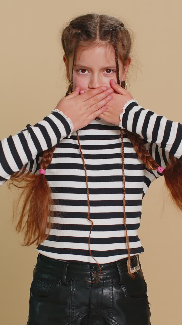 Bambina spaventata che chiude la bocca con le mani rifiutandosi di dire un terribile segreto incredibile verità