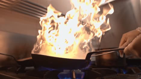 flambé cooking with open flame in a frying pan