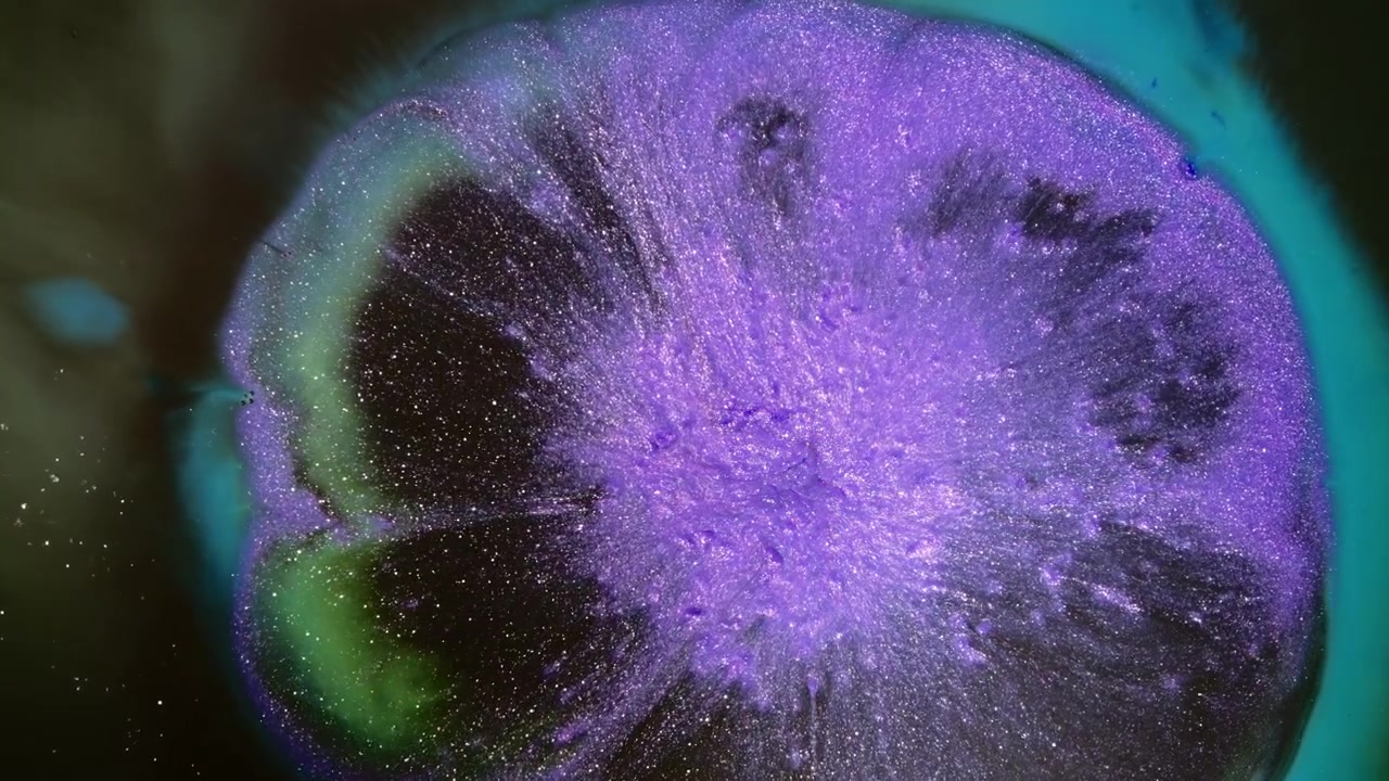 Purple metallic ink spreads outward into a circular bloom as a turquoise ring pulses around it in close-up macro.