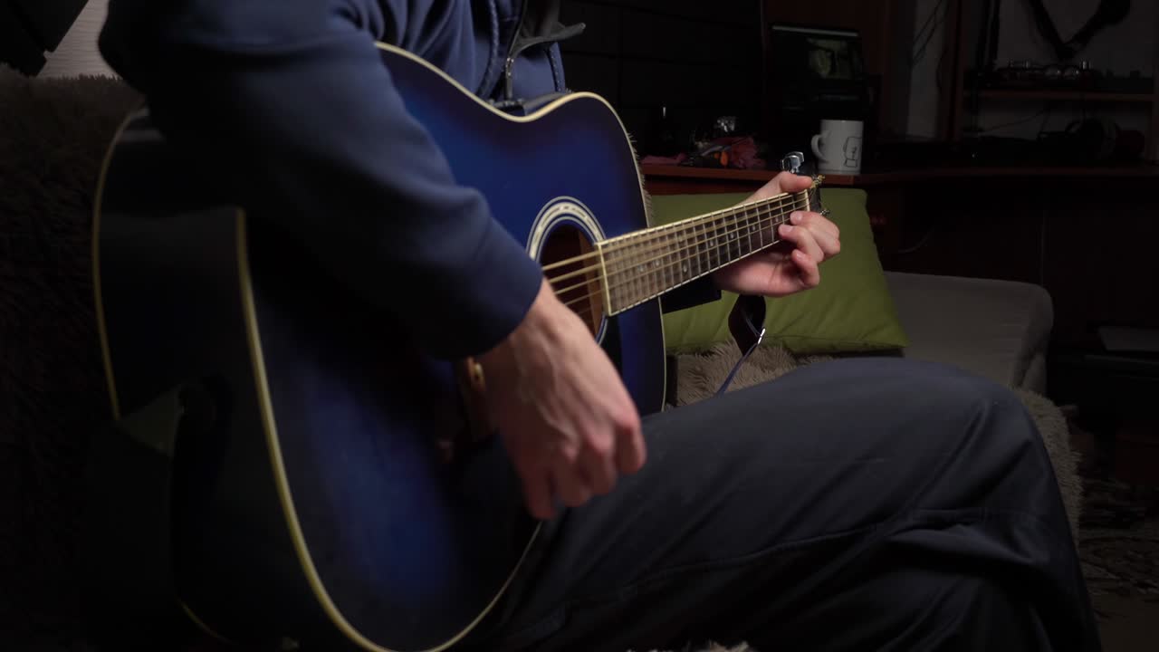 hombre toca una pica en una guitarra moderna en la oscuridad