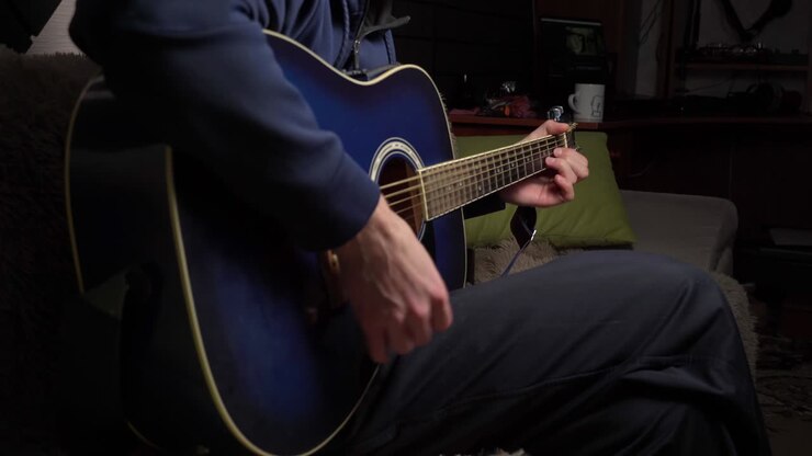 un homme joue d'une guitare moderne dans le noir.