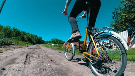 young woman riding vintage bicycle along a rural road in a village. slow motion