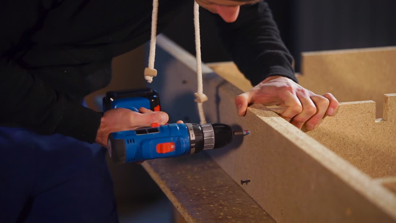 hombre usando un taladro eléctrico para montar muebles de madera
