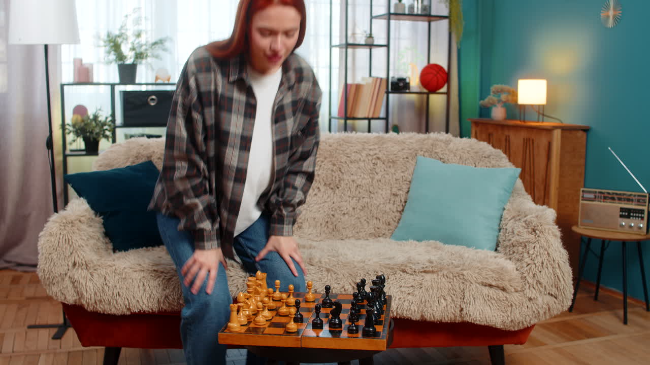 Woman on sofa playing chess against herself smiling having fun with playful split personality mood