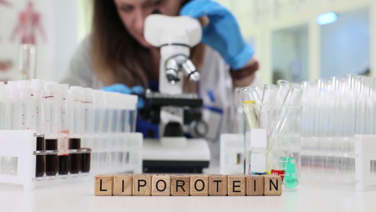 Wooden blocks spell lipoprotein near lab microscope and scientist