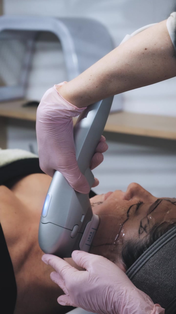 Cosmetologo/a che esegue un trattamento di lifting facciale ad ultrasuoni su un cliente