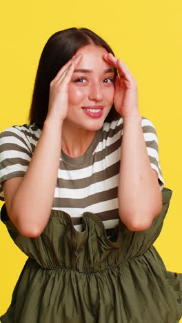 woman hiding face behind hands then peeking out with shy gentle smile expressing bashful reaction