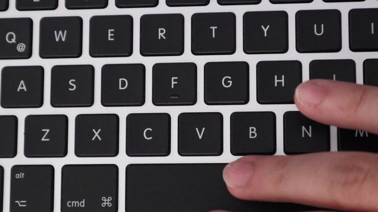 Hand Presses Letter Buttons On Modern Laptop Keyboard, close up, overhead shot