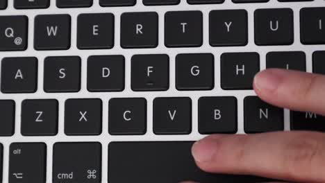 hand presses letter buttons on modern laptop keyboard, close up, overhead shot