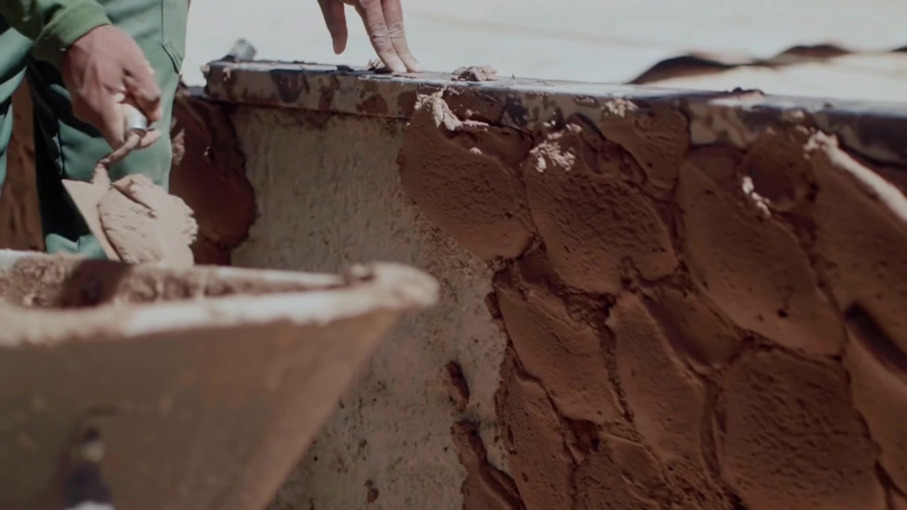 Slow motion shot of a worker applying a mix of clay and sand plaster. Natural building materials for an environmentally friendly home