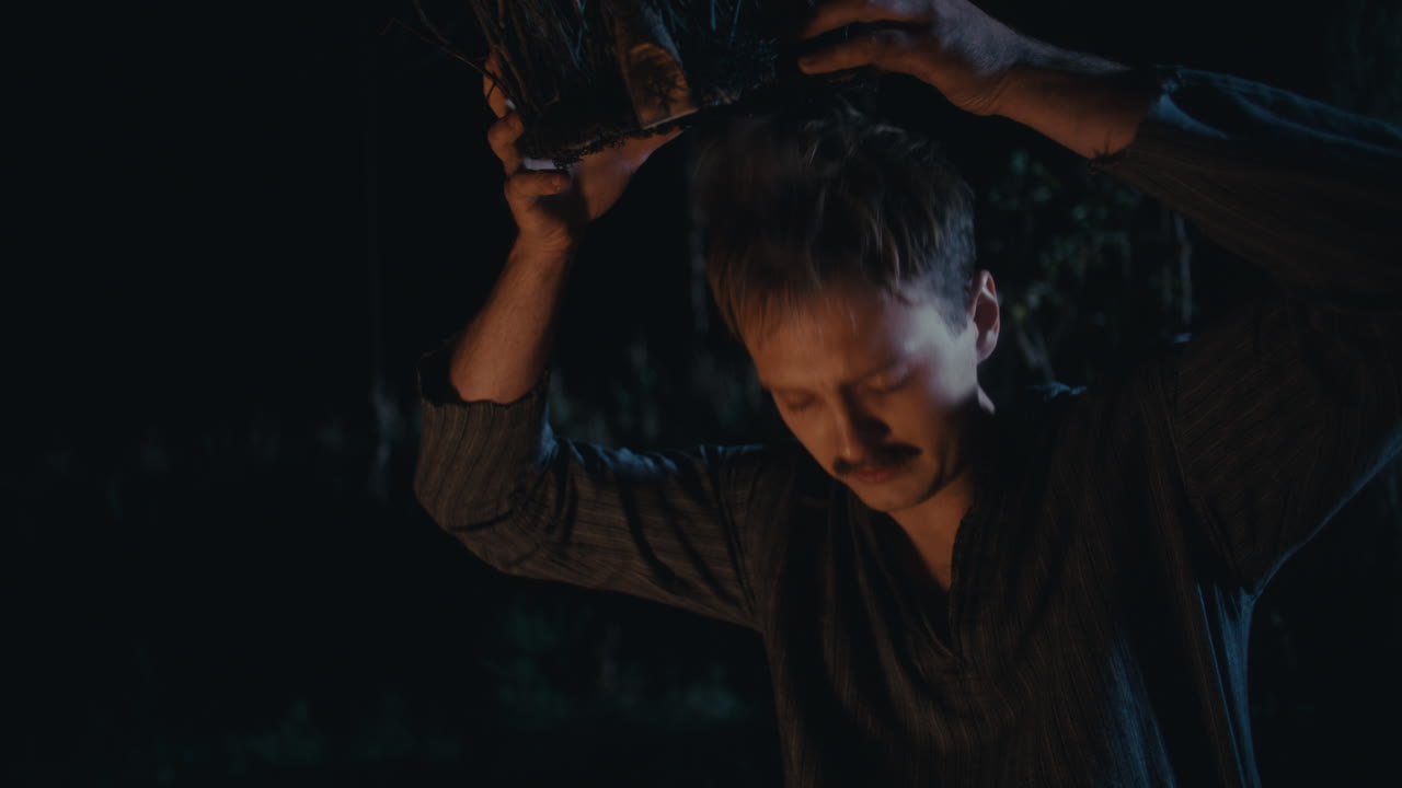 Man performs a mysterious ritual with branches at night