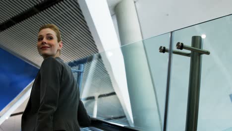 mujer de negocios de pie en una escalera mecánica