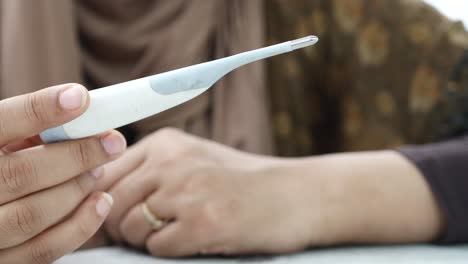 close up of women holding a digital thermometer