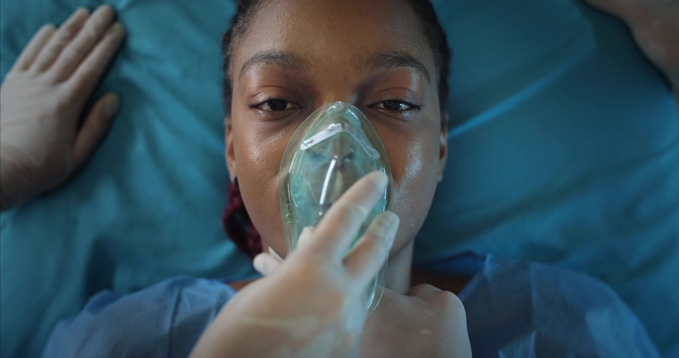 Ung afroamerikansk kvinnlig patient får syrgasmask