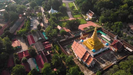 4k thai temple, drone fly toward over thai golden temple, thailand traditional culture, thai buddhism wat, asia travel destination, peaceful calm scenic, green paddy field, camera tilt down, cinematic