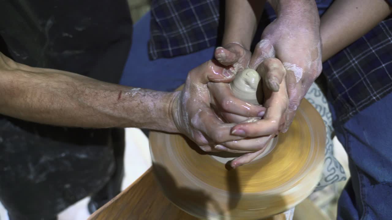 Hands shaping clay on a pottery wheel