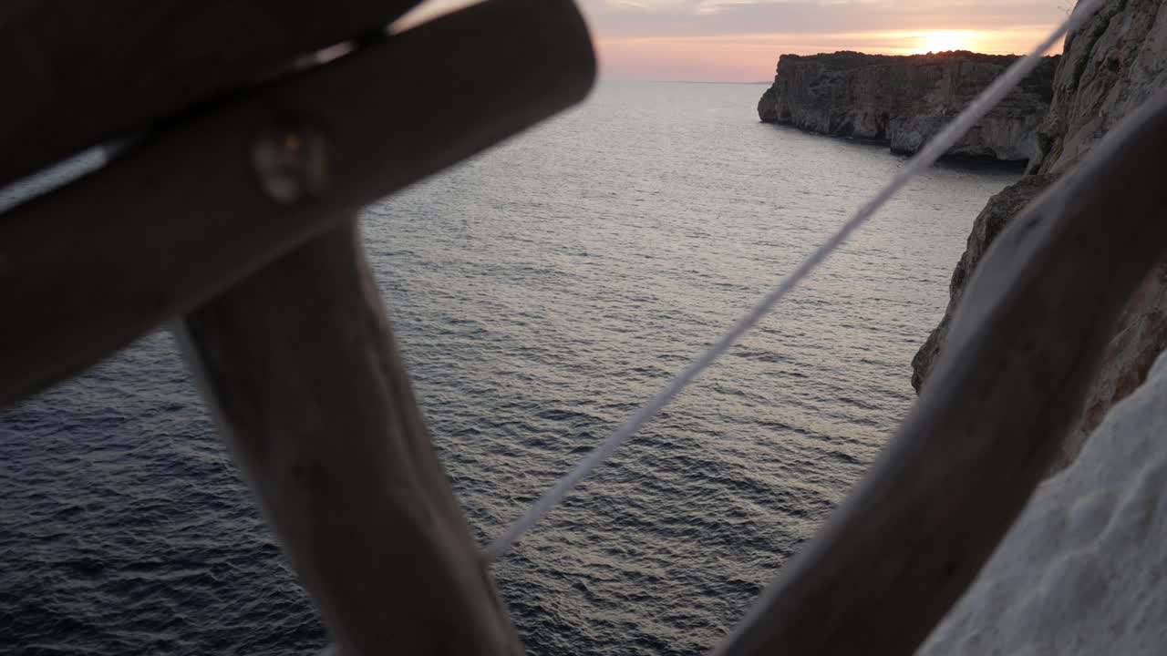 View of the ocean from Cova D'En Xoroi with a wooden frame in the foreground