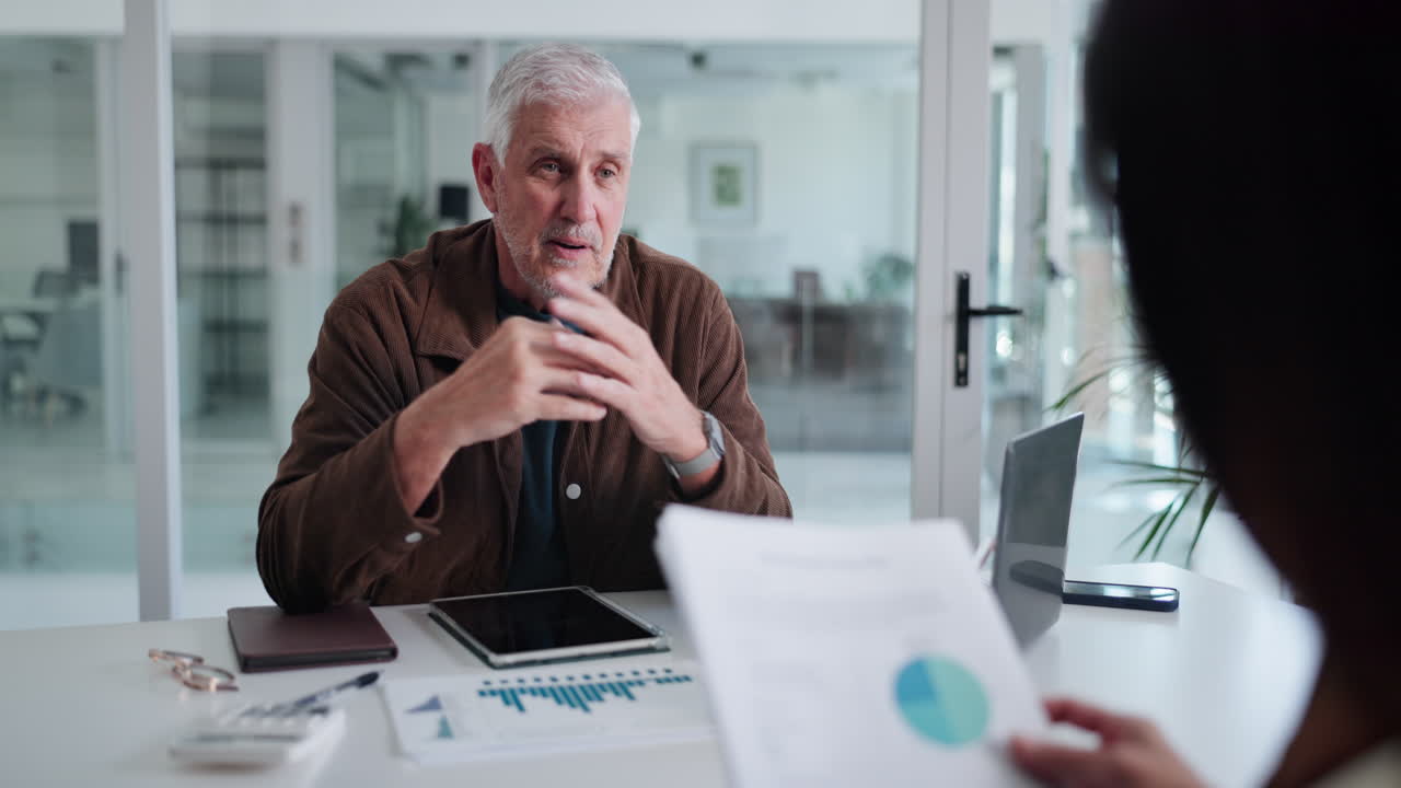 Senior Businessman Discussing Charts and Graphs in a Modern Office