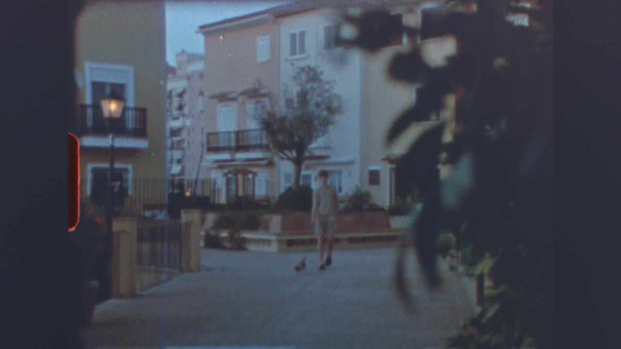 Vintage footage of a person walking a dog through a residential area