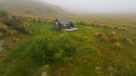 Cabaña-De-Espuelas-En-Mackenzie,-Nueva-Zelanda,-Con-Un-Excursionista-Relajándose-En-La-Terraza-Después-De-Una-Larga-Caminata