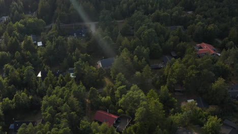 High-angle-footage-of-vacation-houses-or-cottages-in-sparse-forest.-Buildings-protected-by-trees.-Denmark