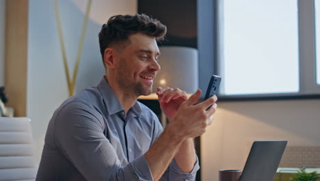 laughing ceo browsing internet getting funny sms mobile phone in office closeup