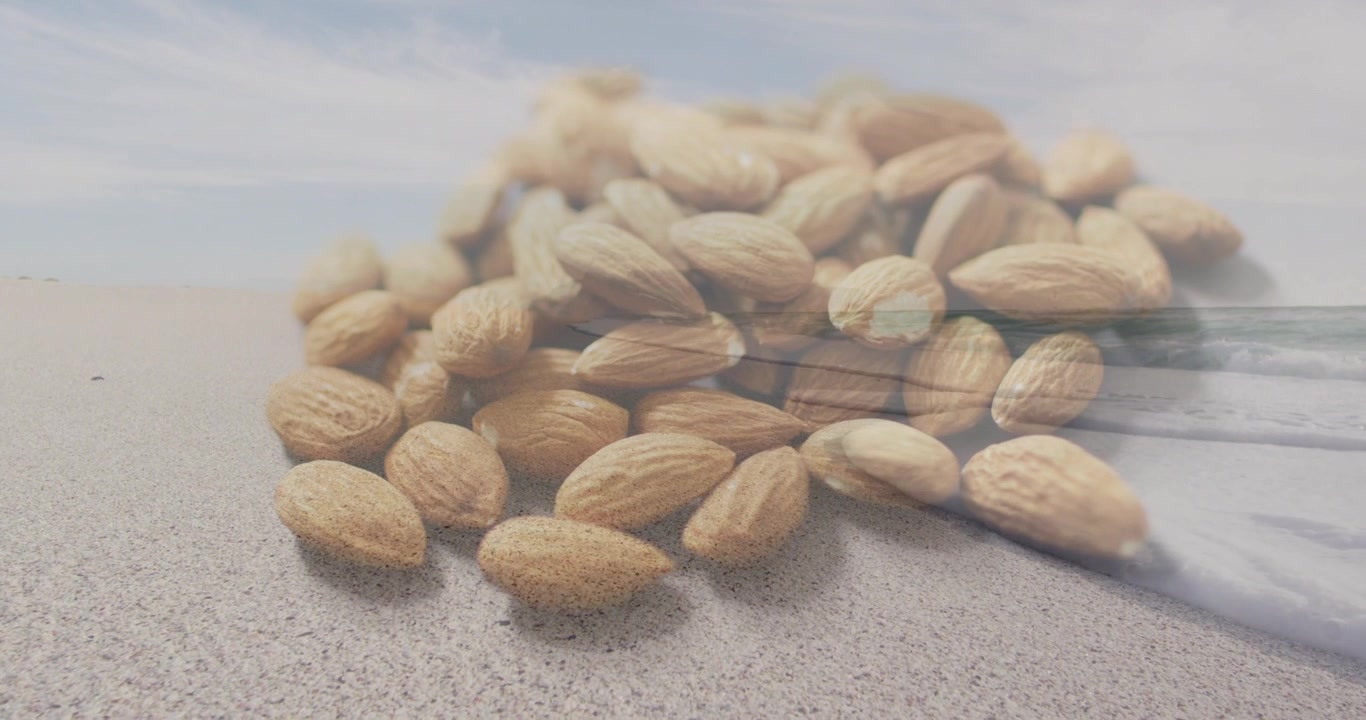 Riproduzione in avvio, con una sovrapposizione d'acqua che scorre su mandorle non sgusciate adagiate sulla sabbia, per marketing alimentare.