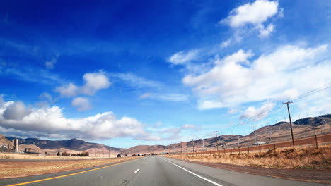 Conduciendo-Por-La-Carretera-En-El-Sur-De-California-Mientras-Las-Turbinas-Eólicas-En-La-Ladera-Generan-Energía-Alternativa