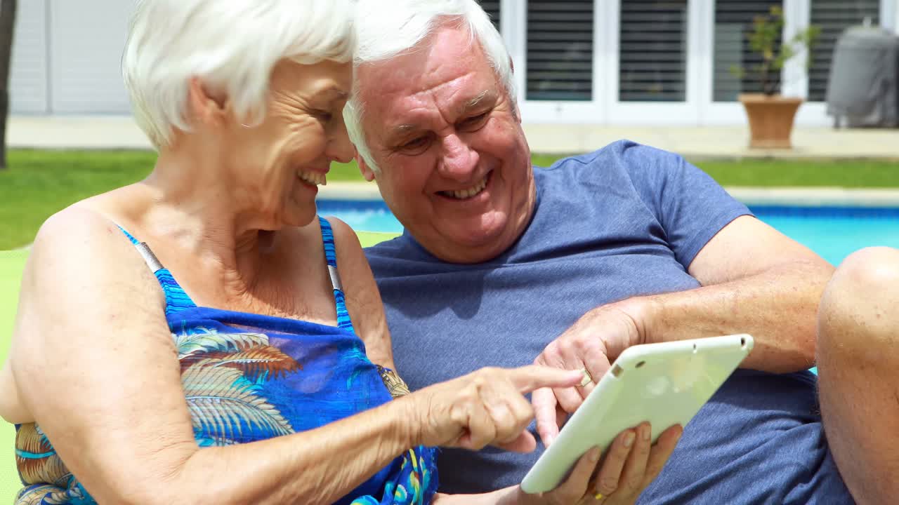 Seniorpar bruger tablet på en liggestol.