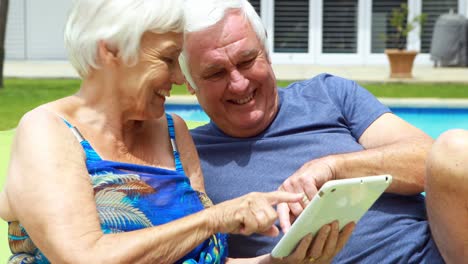 senior couple using digital tablet on lounge chair