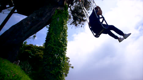 happy young man in ecuador on rope swing in nature, side slo-mo