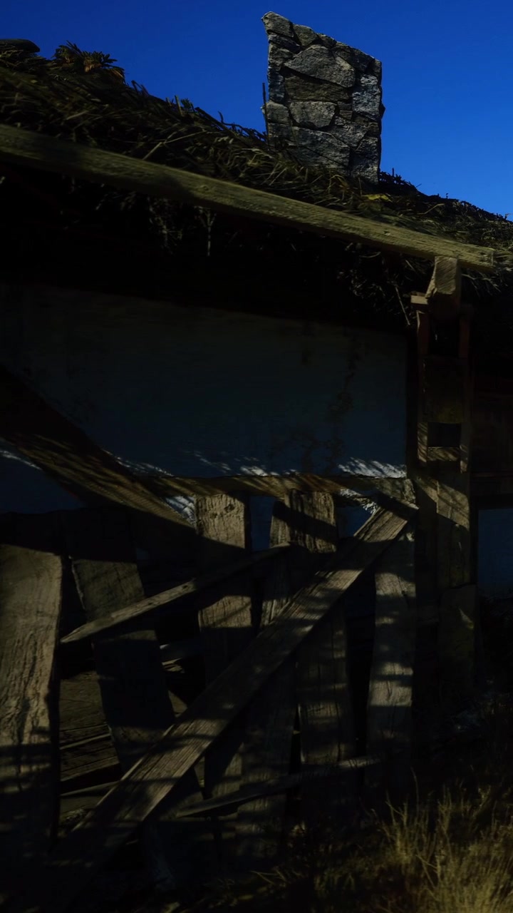 Vecchia struttura in legno con tetto rotto sotto un cielo blu in una zona rurale.