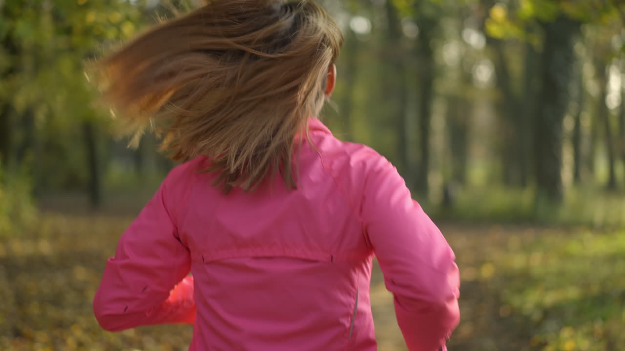 Woman with blonde hair running through a sunny autumn park