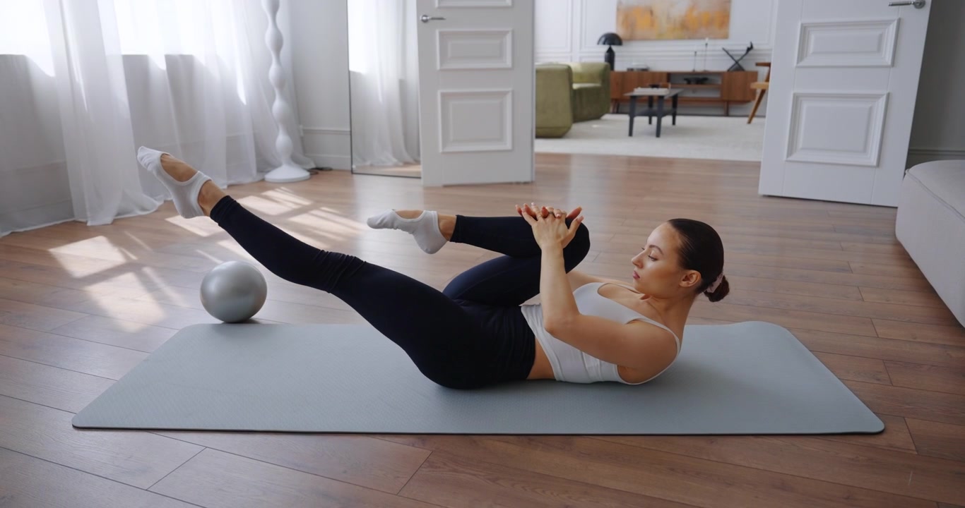 Young Woman Performing Pilates Single Leg Stretch Exercise at Home