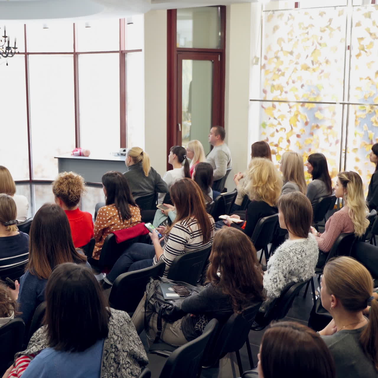 Many adults sitting in a modern auditory. Speaker man discussing about marketing and management strategy on the stage of a hall. Seminar concept.