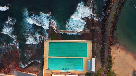 Rising-sped-up-view-of-People-Swimming-In-Continental-Pool-and-Waves-Crashing