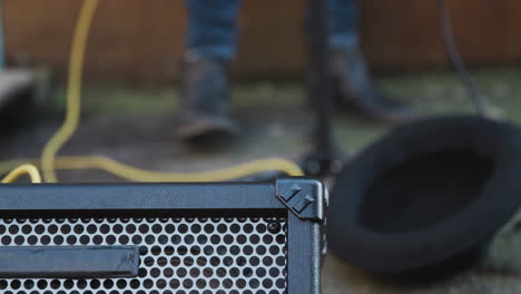 close up of hat for money at feet of female musician busking playing guitar and singing outdoors