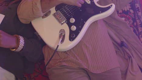 happy young girl playing guitar while lying on floor with her friend during rehearsal in recording studio