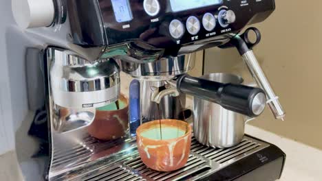a hand operates an espresso machine, brewing coffee into a cup. bright lighting highlights the stainless steel finish