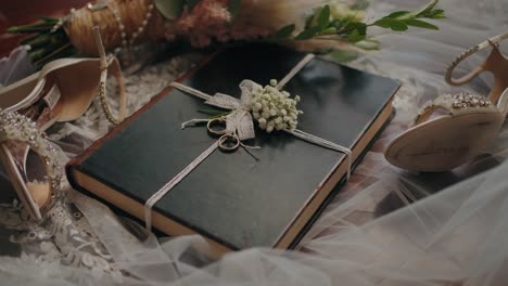 wedding rings on journal with lace flowers and bridal shoes
