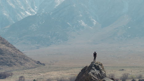 hiker on top of rocky peak looking at sierra nevada mountain range, aerial